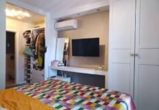 Стильная спальня с телевизором и шкафом, современный дизайн, комфортабельная обстановка, уютное место для отдыха.