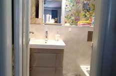 Маленькая современная ванная комната с зеркалом, цветами и предметами гигиены.