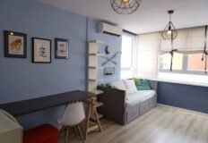 Красивая уютная комната с мягким диваном, яркими подушками и светлой отделкой, окна с жалюзи, стильное освещение и декоративные элементы для комфортного проживания.