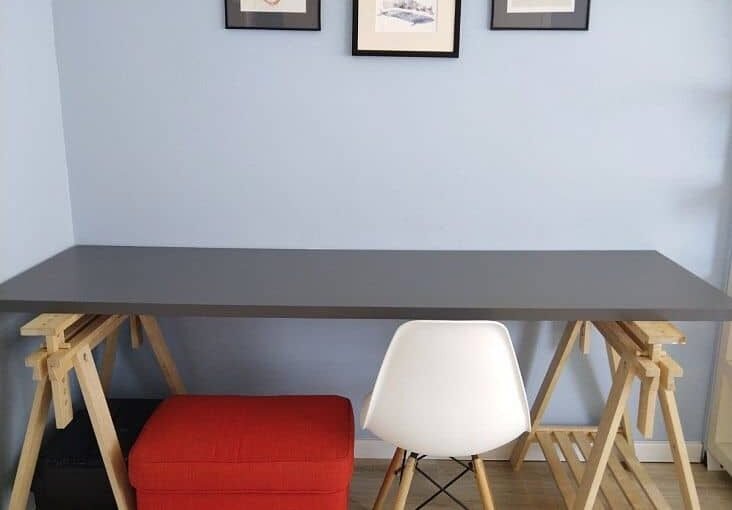 Вид рабочего столика в современном интерьере с стулом и украшенной стеной.