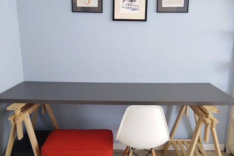 Вид рабочего столика в современном интерьере с стулом и украшенной стеной.