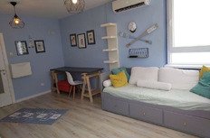 оригинальный интерьер гостиной с уютной мебелью и морской тематикой, светлая палитра и удобный диван с яркими подушками, стильные настенные украшения, большие окна для естественного освещения.