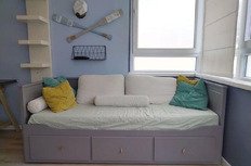 Комфортабельный диван-кровать в современной гостиной с яркими подушками и спортивной декорацией, оптимальное решение для уютного отдыха.