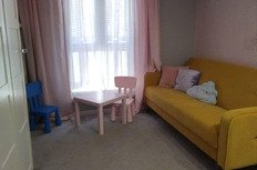 уютная гостиная комната с яркой желтой мягкой мебелью и детскими игрушками, светлый дизайн интерьера, большие окна с легкими шторами, приятная атмосфера для отдыха и развлечений в квартире Eurodomestate.com.