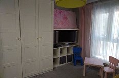 Детская комната с телевизором, шкафом и детской мебелью, уютное пространство для ребенка в современном стильном интерьере.